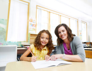 Teacher and young student smiling at the camera