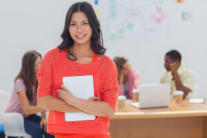 Teacher in orange shirt smiles at camera