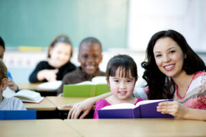 Smiling teacher with class of young students reading