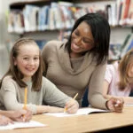 Black teacher smiles at white student