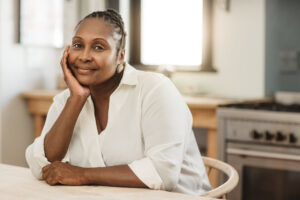 Portrait of a mature African American woman smiling contently while sitting at her kitchen table in the morning