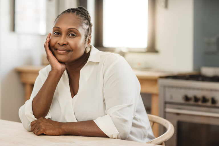 Portrait of a mature African American woman smiling contently while sitting at her kitchen table in the morning