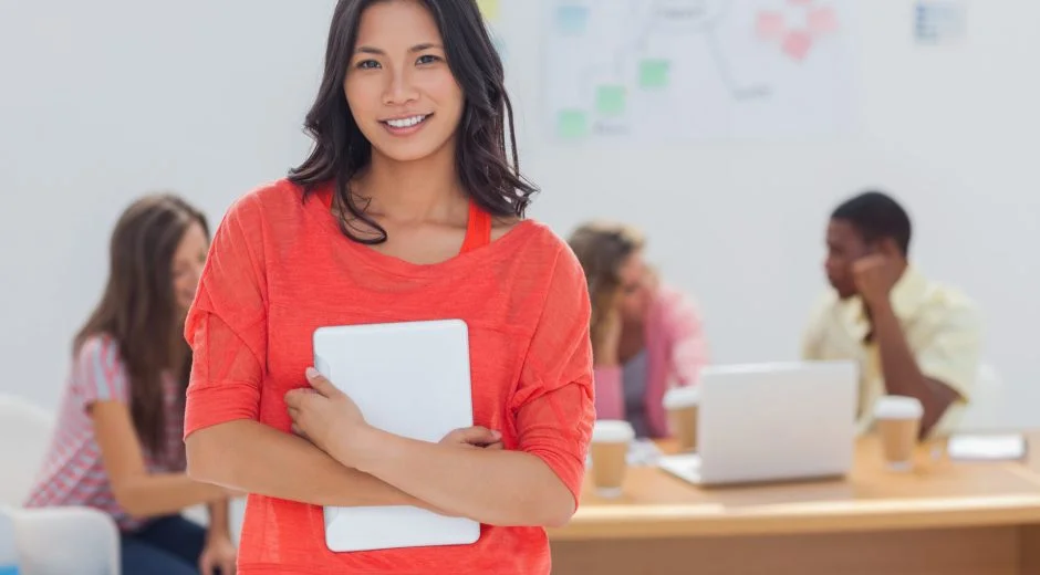 Teacher in orange shirt smiles at camera