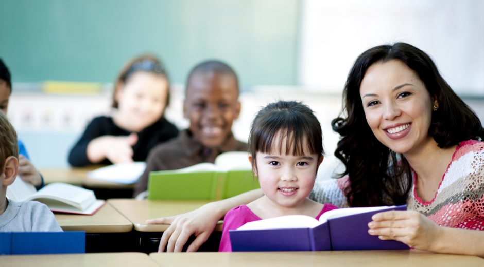 Smiling teacher with class of young students reading