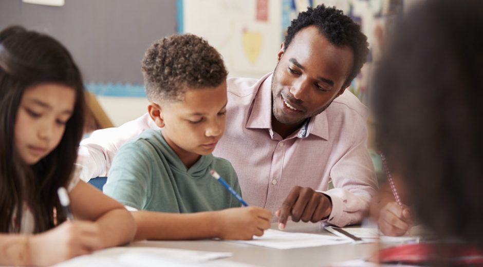 Male African American Teacher helping young student