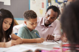 Male African American Teacher helping young student